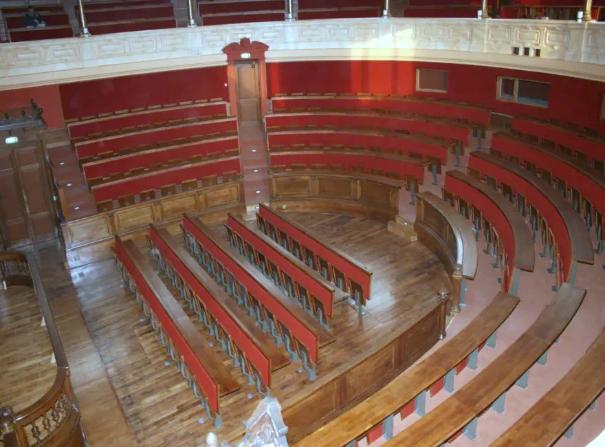Amphithéâtre ancien à gradins de bois, sièges et sol rouges